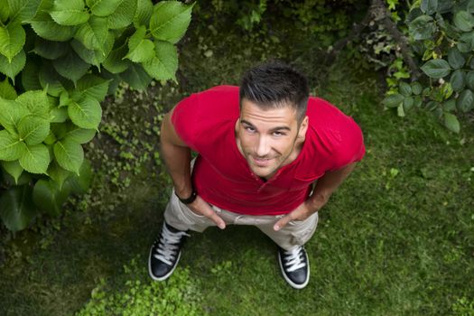 Good looking, fit male model looking up with smile, outdoors on grassland, shot from above