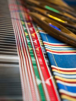 Weaving shuttles and colorful textile with pattern. Artistic shallow DOF