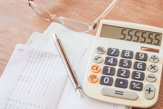 Calculator, pen and eyeglasses on bank account passbook, stock photo