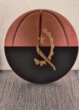 Basketball with flag of Angola, over wooden surface