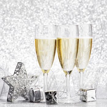 Glasses of champagne and christmas decoration on silver background