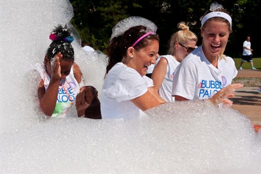Lawrenceville, GA, USA - May 31, 2014:  Women laugh while emerging from a cloud of foamy soap suds at Bubble Palooza.