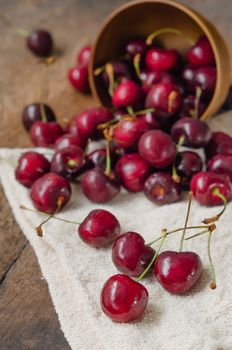 fresh s cherries spilling out from the bowl on wooden table  background