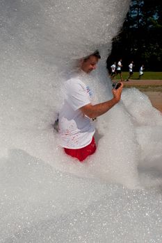 Lawrenceville, GA, USA - May 31, 2014:  A man takes a selfie with a Go Pro camera as he emerges from the foamy soap suds at Bubble Palooza.