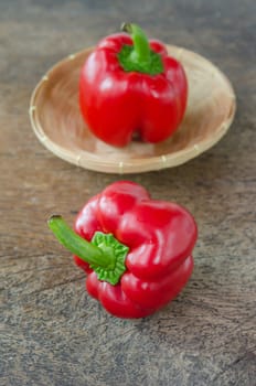 red bell peppers on wooden table and one in basket
