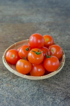 Red cherry tomatoes  in basket on  wooden background