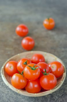 close up red cherry tomatoes  in basket on wooden background