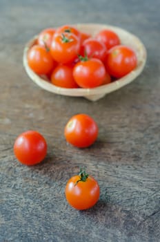 Red cherry tomatoes  on a textured  wooden background and basket