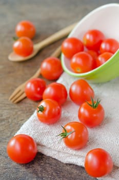 Red cherry tomatoes  spilling out from bowl with spoon and fork