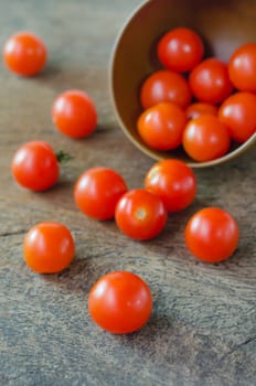Red cherry tomatoes  spilling out from brown bowl