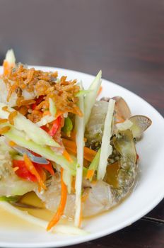 spicy mango salad with  raw crab on dish over wooden table