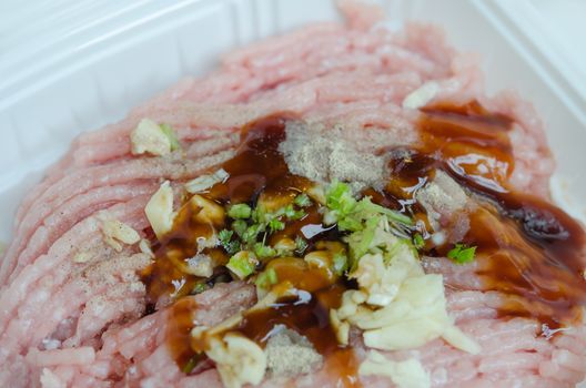 Plastic packaging with raw ground beef with sauce and garlic
