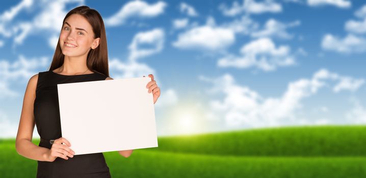 Businesswoman holding paper sheet. Blue sky and green grass as backdrop