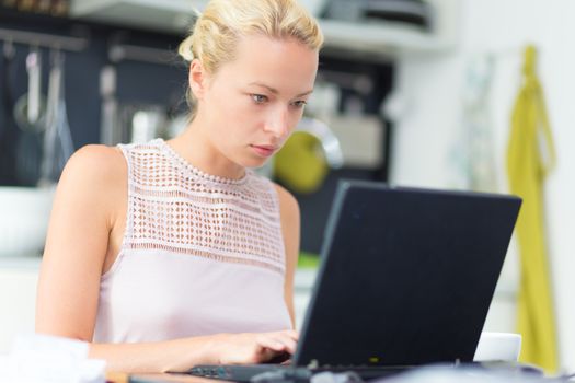 Business woman working remotly from her dining table. Home kitchen in the background.