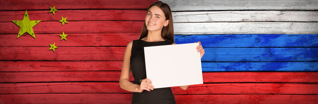 Businesswoman holding paper sheet. China and Russian flags as backdrop