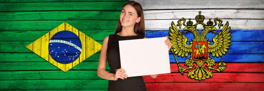 Businesswoman holding paper sheet. Brazil and Russian flags as backdrop