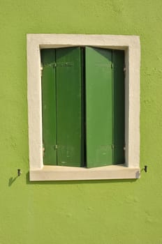 Green shutters on a vivid green wall in the island of Burano, Venice, Italy
