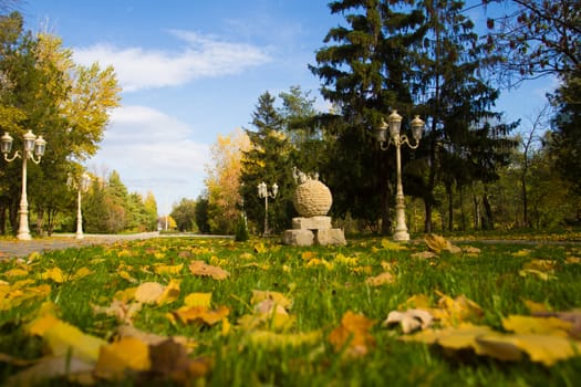 Autumn city park. Green grass, yellow foliage and blue sky - Stock Photo