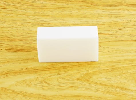 A white bar of soap, rectangle shap, placed on a wooden table.                              