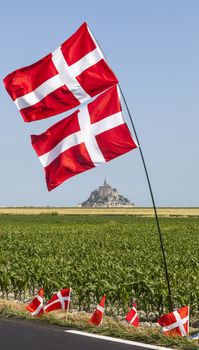 Image of the famous Mont Saint Michel Monastery, partially framed by Norwegian flags, on the roadside during the stage 11 of the edition 100 of Le Tour de France 2013, a time trial between Avranches and Mont Saint Michel.