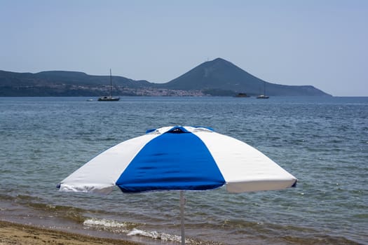 Blue and white beach umbrella - Sea and mountains behind it