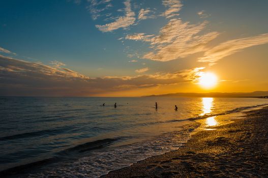 silhouette of four boys playing with a ball in the sea at the end of the day