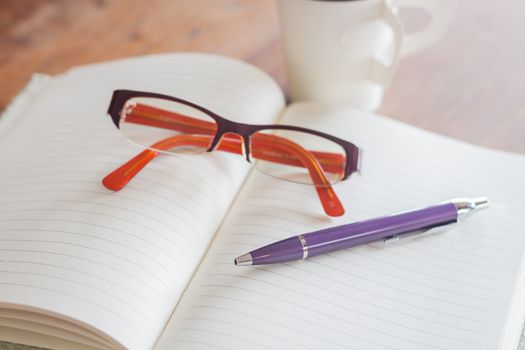 Pen and eyeglasses on notebook, stock photo