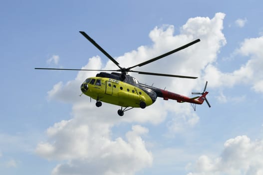 The yellow MI-8 helicopter flies against clouds