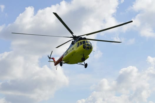 The yellow MI-8 helicopter flies against clouds