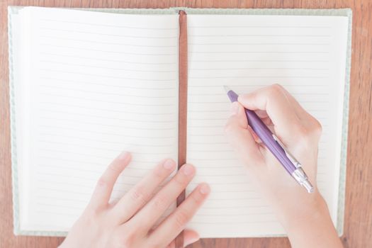 Woman writing on her notebook, stock photo