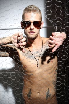 Handsome tattooed Caucasian man rips the mesh,