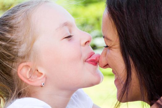 Photo of kissing mother and daughter in summer