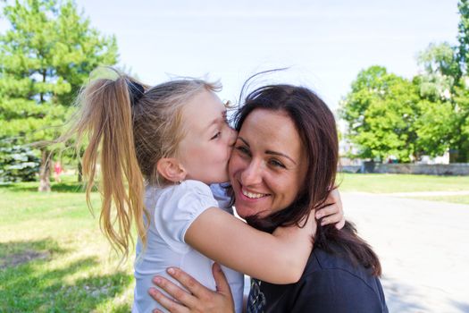 Photo of kissing mother and daughter in summer