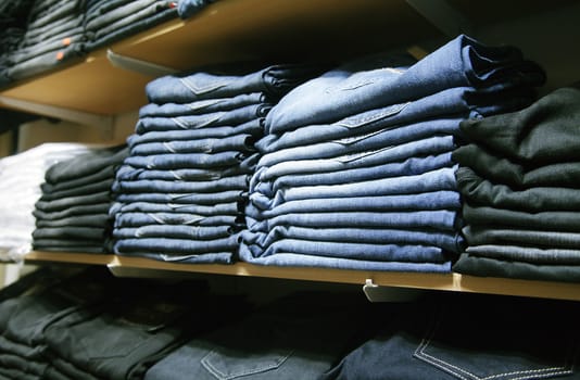 Many folded jeans on shelves in a shop