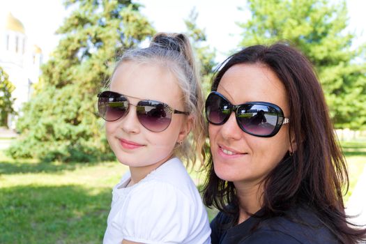 Photo of smiling mother and daughter in sunglasses