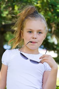 Cute girl playing with sunglasses in summer