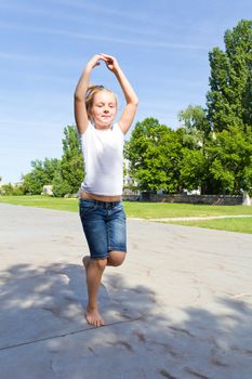 Cute girl with blond hair jumping on one leg