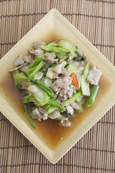 Fried pork with vegetable oil Rectangular plate placed on a wooden plate.