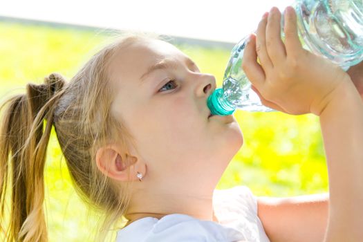 Cute girl with blond long hair drinking water
