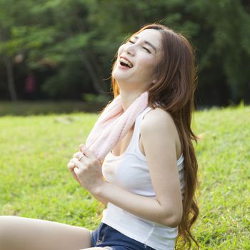 Young woman laughing on the lawn. After a workout in the park.