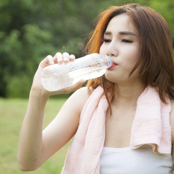 Woman standing water breaks during exercise. Jogging in the park during the evening.