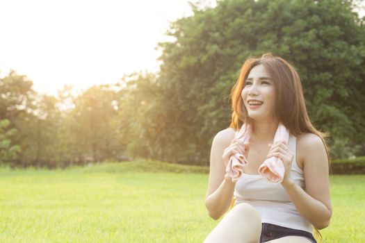 Woman Sitting after jogging. on grass in the park. In the evening