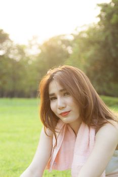 Woman Sitting after jogging. on grass in the park. In the evening