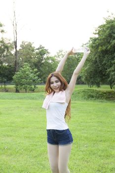 Woman warming up before exercise. on grass Within the park in the evening