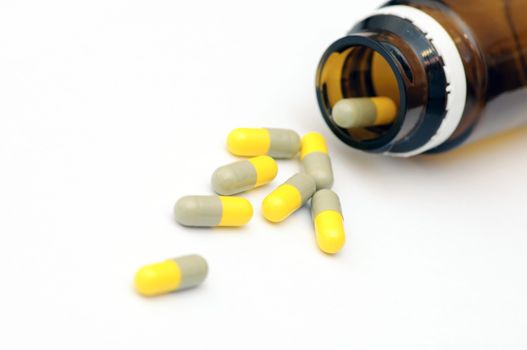 Yellow capsules and phial on white