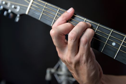 Close-up of the fingering for a G major chord on a left handed classical guitar.
