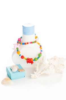 white lotion bottle with color necklace and seashells