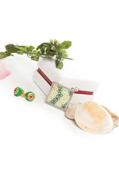 green earrings and medal with white box and stones and clam