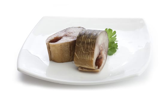 Two pieces of smoked mackerel with fresh green parsley on the white plate