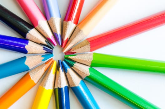 Close up detail of colorful pencils arranged in circle on white background